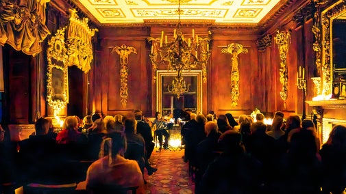 A concert in the Saloon at Lyme, lit by dozens of flickering candles.